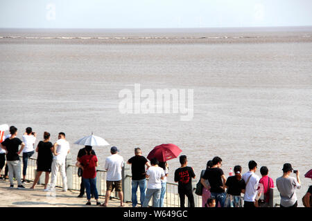 Les visiteurs et les résidents watch ondes d'un mascaret de rivière Qiantang jaillissant sur la rive du fleuve à Haining City, Zhejiang en Chine est de bauvin Banque D'Images