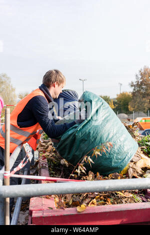 L'homme en vert déchets donnant sur le centre de recyclage de contenants Banque D'Images