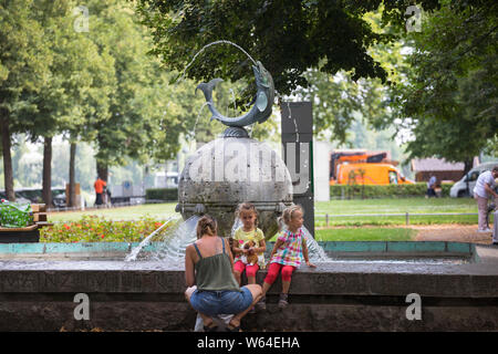 La mère et les filles profiter de rester à la fontaine dans la ville de Mainz, Allemagne Banque D'Images