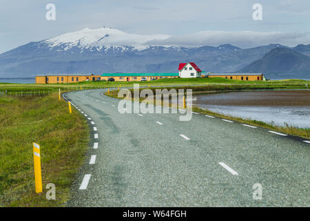 Paysage de campagne traditionnelle islandaise. Une seule maison blanche au toit rouge sur vert prairie avec vue sur la montagne. Empty road, voyage en voiture autour de Banque D'Images