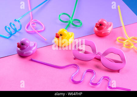 Funky coloré de l'été mise à plat avec les articles drôle - pailles, de canards en caoutchouc, lunettes de forme de lèvre. Rose et violet fond duotone. Banque D'Images