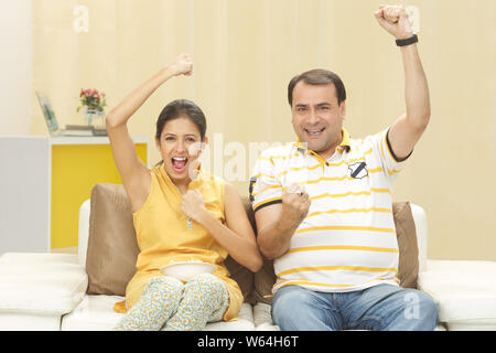 Homme regardant la télévision avec sa fille et applaudisant Banque D'Images