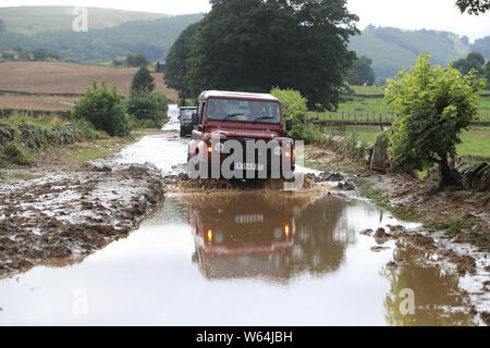 Une voiture conduit le long d'une route inondée dans Grinton, Yorkshire du Nord, après des parties de la région avait 82,2 millions jusqu'à mm de pluie en 24 heures mardi. Banque D'Images