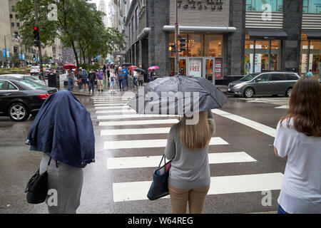 Des parasols et des femmes manteau sur stand à tête en attente de concordance dans la pluie sur Michigan Avenue, downtown Chicago IL États-unis Banque D'Images