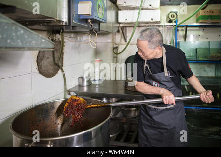 Un homme fait chinois assaisonnement piquant plat-réchaud comme son fils prépare un gâteau d'anniversaire de 'spicy hotpot' avec la forme de piquant chafi Banque D'Images