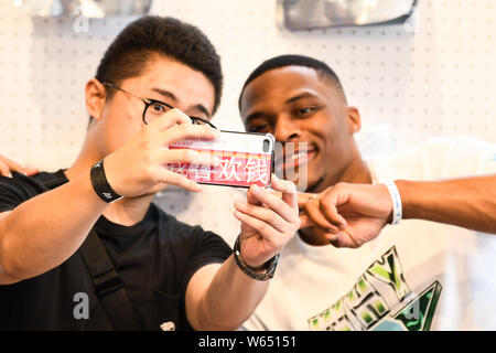 Star de la NBA Russell Westbrook des Oklahoma City Thunder, droite, avec un ventilateur autoportraits prend à un fan meeting événement au cours de sa visite en Chine à Shanghai, Chine, Banque D'Images