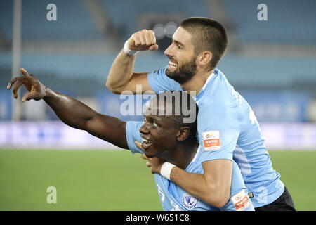 Joueur de football zimbabwéen Nyasha Mushekwi de Dalian Yifang, abaisser, célèbre avec son coéquipier joueur belge de football Yannick Ferreira Carrasco après Banque D'Images