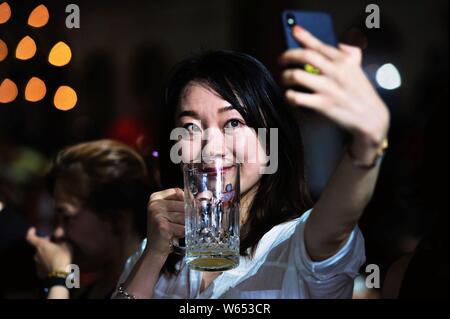 Une femme prend un touriste chinois qu'elle aime selfies bière pendant le 28e Festival International de la bière à Qingdao dans la ville de Qingdao, Shandong en Chine de l'Est Banque D'Images