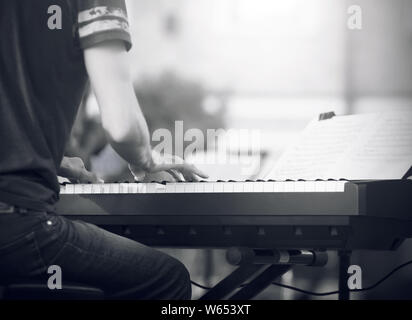 Image en noir et blanc, où un pianiste, vêtu d'un t-shirt et jeans, joue une belle mélodie sur le synthétiseur à un concert Banque D'Images