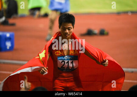 Su Bingtian de Chine pose avec le drapeau national chinois pour célébrer après avoir remporté le 100 m de la finale de la compétition d'athlétisme au cours de l'Asi 2018 Banque D'Images