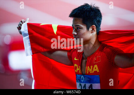 Su Bingtian de Chine pose avec le drapeau national chinois pour célébrer après avoir remporté le 100 m de la finale de la compétition d'athlétisme au cours de l'Asi 2018 Banque D'Images