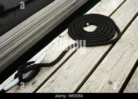 Tourbillonné noir Corde d'amarrage attaché sur un bateau pour fixation Bitt Jetty Banque D'Images