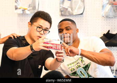 Star de la NBA Russell Westbrook des Oklahoma City Thunder, droite, avec un ventilateur autoportraits prend à un fan meeting événement au cours de sa visite en Chine à Shanghai, Chine, Banque D'Images