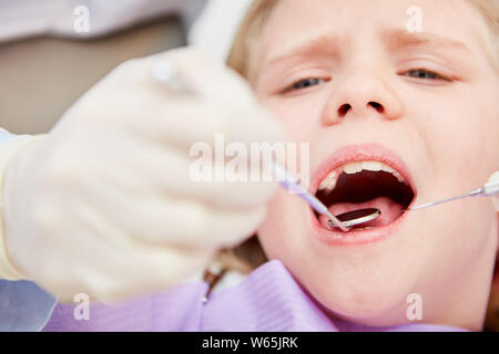 Dentiste traite ou examine les dents d'une petite fille au cours de contrôle de précaution Banque D'Images