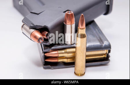 Deux magazines chargés, l'un pour un pistolet 9 mm et l'autre pour un fusil de calibre 223 sur un fond blanc Banque D'Images