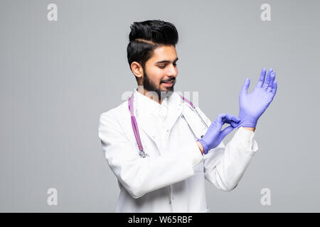 Indian male medic organisant des gants en latex bleu en main isolé sur fond blanc studio Banque D'Images