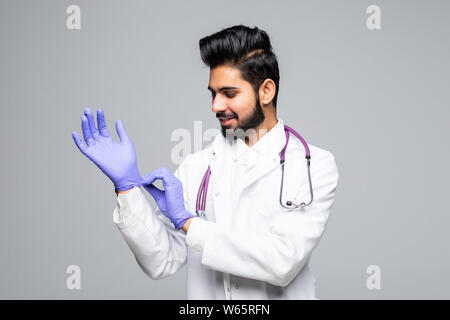 Indian male medic organisant des gants en latex bleu en main isolé sur fond blanc studio Banque D'Images