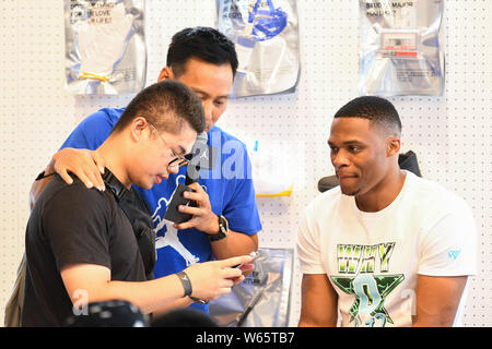 Star de la NBA Russell Westbrook des Oklahoma City Thunder, droite, avec un ventilateur autoportraits prend à un fan meeting événement au cours de sa visite en Chine à Shanghai, Chine, Banque D'Images