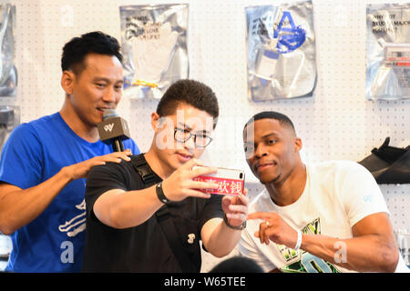 Star de la NBA Russell Westbrook des Oklahoma City Thunder, droite, avec un ventilateur autoportraits prend à un fan meeting événement au cours de sa visite en Chine à Shanghai, Chine, Banque D'Images