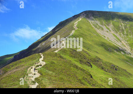 Lone Fellwalker marche sur neige fondue comment le Wainwright 'Grisedale Pike' dans la vallée de l'Coldale dans le Parc National du Lake District, Cumbria, England, UK. Banque D'Images