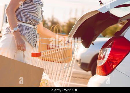 Woman putting de sacs en papier avec de la nourriture dans coffre de voiture Banque D'Images