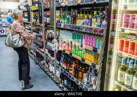 Une femme regarde la sélection de vins à vendre sur des étagères dans un Foodhall Marks and Spicers. Banque D'Images