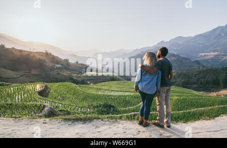 Young Caucasian couple donnant sur les rizières en terrasses de Sapa au coucher du soleil dans la région de Lao Cai du Vietnam Banque D'Images