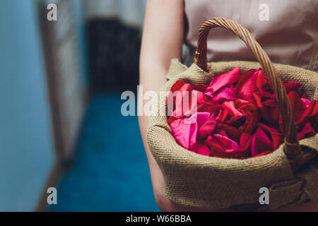 Dans une robe blanche de demoiselle d'organiser la diffusion de paniers de fleurs pétale de rose à une réception de mariage à l'église pour un service d'action de grâces. Banque D'Images
