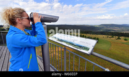 Oberweid, Allemagne. 31 juillet, 2019. Julia Gombert de Landschaftspflegeverband Rhön regarde à travers les jumelles de la voile de Noé dans le plate-forme d'observation de la Réserve de biosphère de Rhön de l'UNESCO. La Rhön est une gare de cette année, la tournée d'été de la forêt de Thuringe, Ministre de l'environnement. La visite conduit sur 9 jours et 24 stations le long de la "Grünen" et "Blauer Band' en Thuringe. Crédit : Martin Schutt/dpa-Zentralbild/dpa/Alamy Live News Banque D'Images