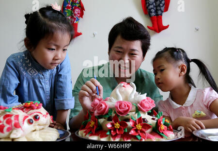 Patrimoine culturel immatériel successeur Wang Xin, centre, apprend aux enfants à faire des petits pains à la vapeur à son domicile à Zaozhuang City, Shandong en Chine de l'est pr Banque D'Images