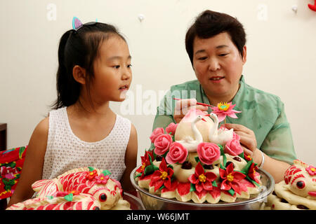 Patrimoine culturel immatériel successeur Wang Xin, droite, enseigne aux enfants de faire des brioches à la vapeur à son domicile à Zaozhuang City, Shandong, Chine orientale pro Banque D'Images