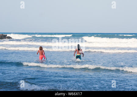 Orihuela Costa, Alicante, Espagne - Juillet 2019 : Deux jeunes hommes cheveux longs à pied à la mer en tenant le surf boards Banque D'Images