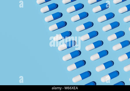 Rangées de capsules médecine bleu et blanc sur un fond bleu clair. Rendu 3D illustration. Banque D'Images