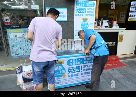 Un homme obtient la livraison de nourriture de boissons sans surveillance un amour 'congélateur' qui fournit gratuitement l'eau et de glace pour les courriers, les gars de livraison de nourriture, la police de la circulation Banque D'Images