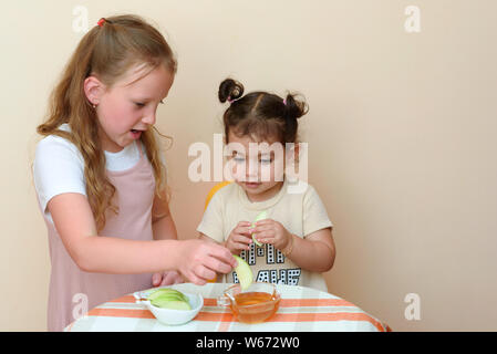 Portrait de deux petites filles funny cute apple manger avec du miel à l'intérieur. Enfants juifs trempant des tranches de pomme dans le miel à Roch Hachana. Banque D'Images