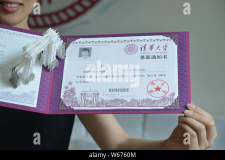 Un enseignant montre la lettre d'acceptation de l'Université de Tsinghua, 2018 avec une sculpture de papier 3D de la deuxième barrière symbolique - la vieille porte" du collège Banque D'Images