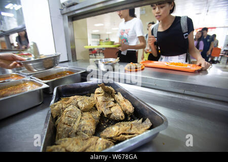 Un personnel chinois sert des plats de poisson, qui sont récoltées à partir de la 210 Daoqian Lake dans le campus de l'Université de médecine de Guangxi, aux étudiants gratuitement à la Banque D'Images