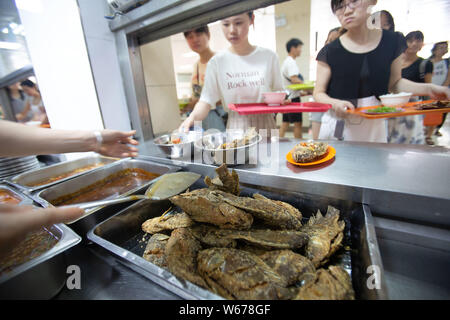 Un personnel chinois sert des plats de poisson, qui sont récoltées à partir de la 210 Daoqian Lake dans le campus de l'Université de médecine de Guangxi, aux étudiants gratuitement à la Banque D'Images