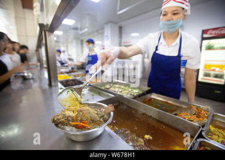 Un personnel chinois sert des plats de poisson, qui sont récoltées à partir de la 210 Daoqian Lake dans le campus de l'Université de médecine de Guangxi, aux étudiants gratuitement à la Banque D'Images