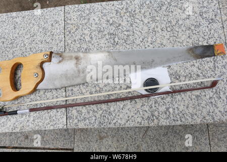 61 ans, ancien musicien chinois Liang Linsheng montre un archet erhu et une scie à bois qu'il utilise pour créer des sons et de la musique à un parc dans la ville de Jilin, nord Banque D'Images