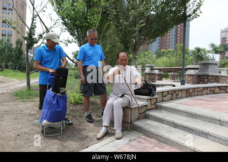 61 ans, ancien musicien chinois Liang Linsheng erhu joue un arc le long du bord d'une scie pour créer des sons et de la musique à un parc dans la ville de Jilin, nort Banque D'Images