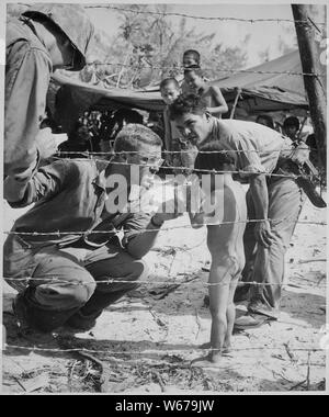 Essayez d'apaiser des marines un enfant qui pleure en offrant un brillant étain rations. Les enfants sont à l'abri avec leur famille dans un camp établi à l'intention des réfugiés de zones de combat de la Marine américaine par les autorités des affaires civiles sur Saipan. ; notes générales : utilisation de la guerre et des conflits Nombre 1268 lors de la commande d'une reproduction ou demande d'informations sur cette image. Banque D'Images