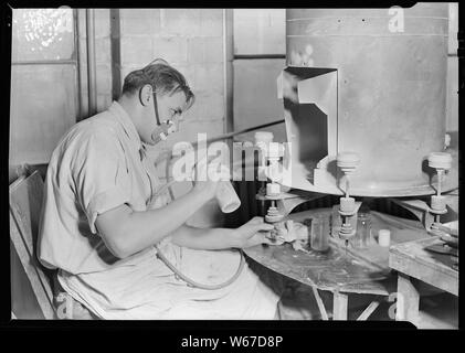 Millville, New Jersey - Bouteilles en verre. Pulvérisateur de peinture, T. C. Wheaton Co. salle d'art. Cet homme est la pulvérisation de pots de crème froide en verre blanc à l'aide d'un flambeau de soufflage. C'est l'un des nouveaux procédés développés par T. C. Wheaton. Les pots sont mis sur le papier par une fille qui est assis à l'autre côté de la machine. Ils tournent autour de ce travailleur qui matinaux. La jeune fille prend alors le pot et le remplace par un nouveau. Banque D'Images