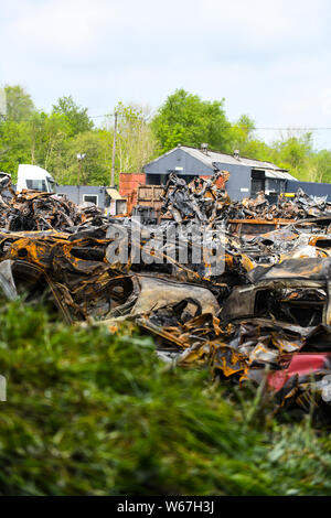 Des tas de voitures brûlées sont pictrured à un parc à ferrailles en Ammanford, Pays de Galles, Royaume-Uni après un incendie, laissant tordus et chard metal partout. Banque D'Images