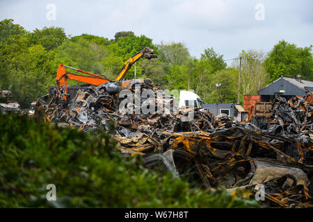 Des tas de voitures brûlées sont pictrured à un parc à ferrailles en Ammanford, Pays de Galles, Royaume-Uni après un incendie, laissant tordus et chard metal partout. Banque D'Images