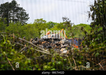 Des tas de voitures brûlées sont pictrured à un parc à ferrailles en Ammanford, Pays de Galles, Royaume-Uni après un incendie, laissant tordus et chard metal partout. Banque D'Images