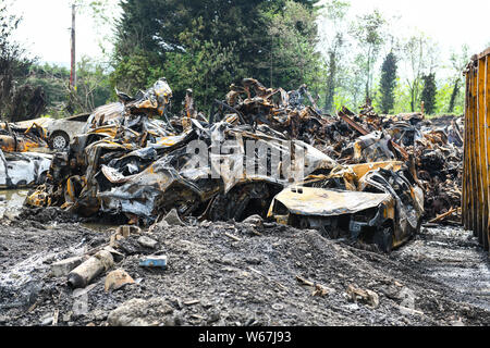 Des tas de voitures brûlées sont pictrured à un parc à ferrailles en Ammanford, Pays de Galles, Royaume-Uni après un incendie, laissant tordus et chard metal partout. Banque D'Images