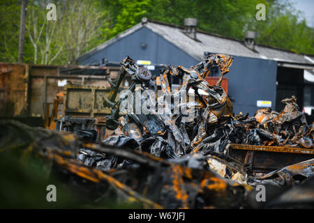 Des tas de voitures brûlées sont pictrured à un parc à ferrailles en Ammanford, Pays de Galles, Royaume-Uni après un incendie, laissant tordus et chard metal partout. Banque D'Images