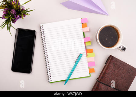 Bloc-notes sur la table de travail avec téléphone gris et du café. Papier blanc vierge sur un bureau de travail Banque D'Images