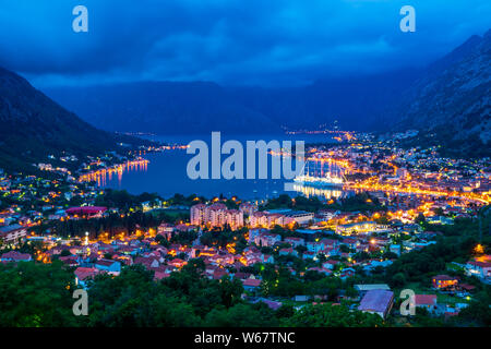 Monenegro, vue au-dessus de maisons, les rues et le port de la baie de Kotor ville avec d'énormes d'ancrage des bateaux de croisière de nuit entouré de nature paysage fantastique Banque D'Images